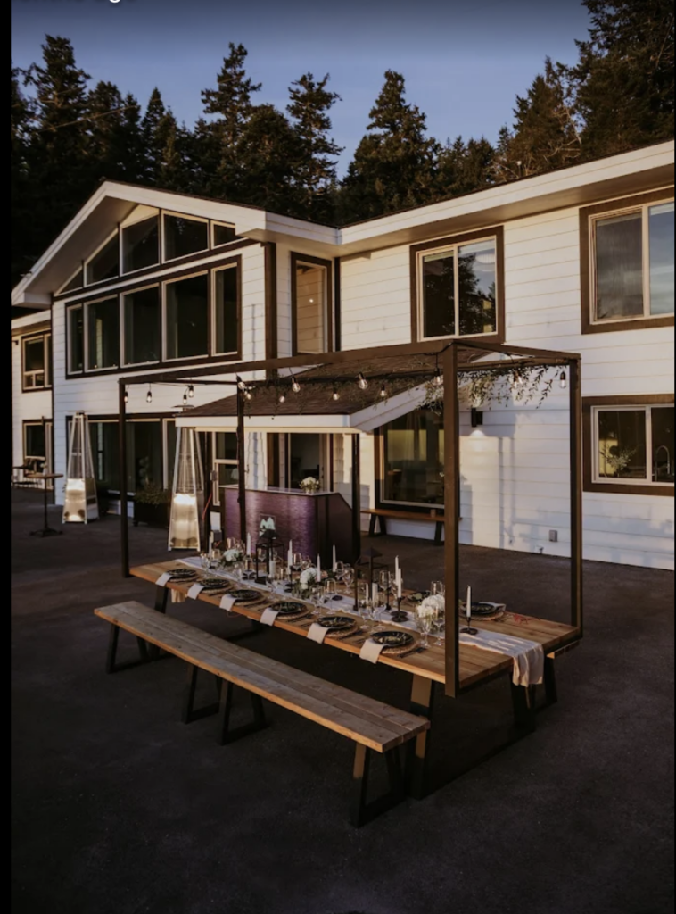 Intimate outdoor reception table at an Oregon Coast wedding venue, set with candles and string lights.